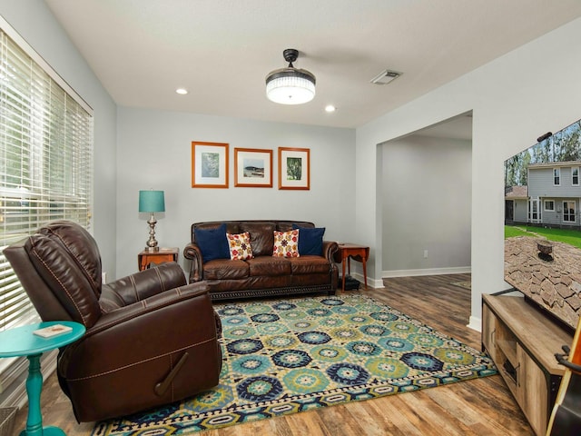 living area with recessed lighting, visible vents, baseboards, and wood finished floors