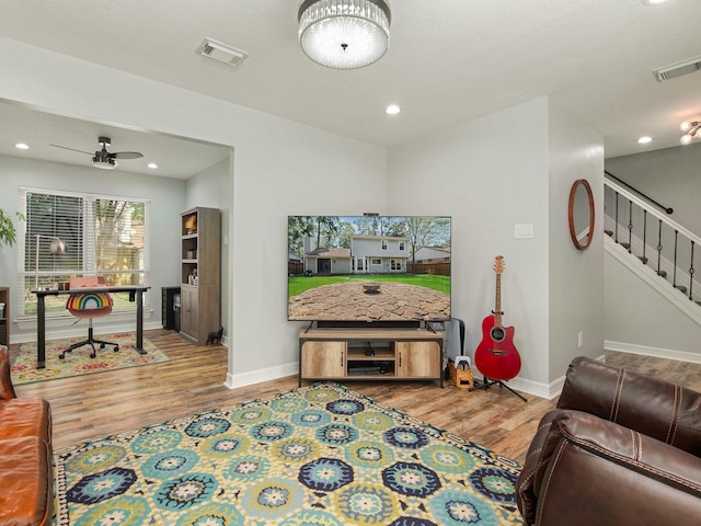 living room featuring visible vents, stairway, baseboards, and wood finished floors