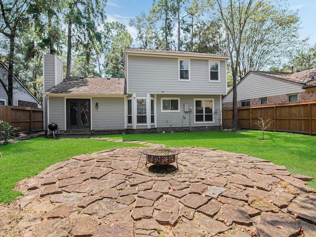 rear view of property featuring a chimney, a lawn, an outdoor fire pit, a patio area, and a fenced backyard