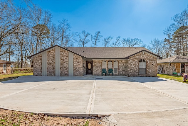 view of front of house with concrete driveway, brick siding, and roof with shingles