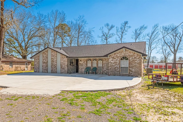 view of front of property with concrete driveway, brick siding, and a shingled roof