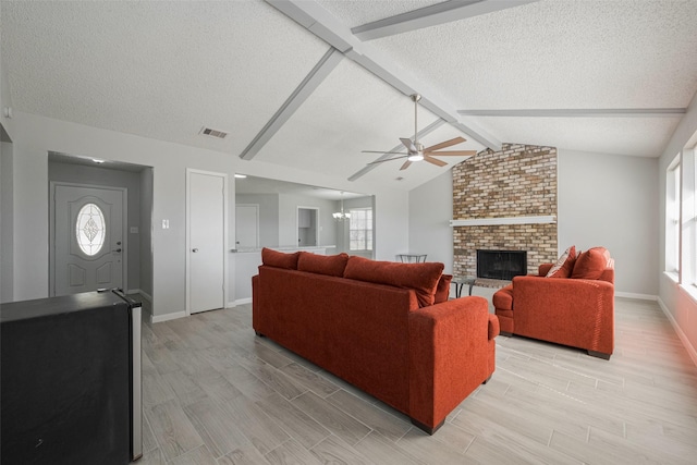 living room featuring lofted ceiling with beams, visible vents, a healthy amount of sunlight, light wood-style floors, and a brick fireplace