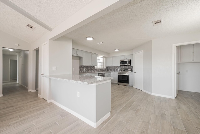 kitchen featuring stainless steel appliances, light wood-type flooring, a peninsula, and visible vents