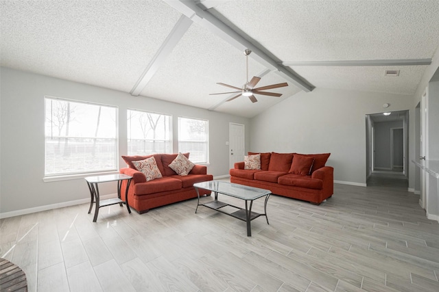 living area featuring lofted ceiling with beams, a healthy amount of sunlight, light wood-type flooring, and a textured ceiling