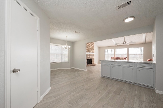 kitchen featuring open floor plan, light wood-style flooring, a fireplace, and visible vents