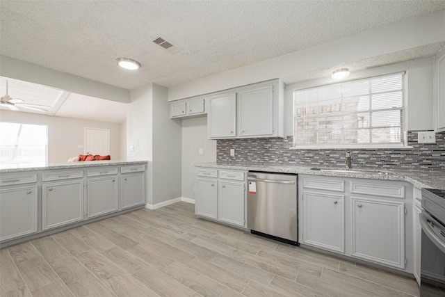 kitchen featuring ceiling fan, a sink, visible vents, dishwasher, and tasteful backsplash