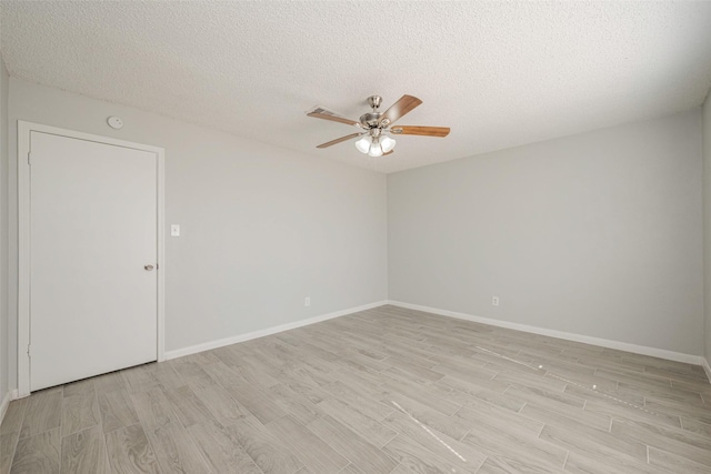 unfurnished room with light wood-style floors, ceiling fan, baseboards, and a textured ceiling