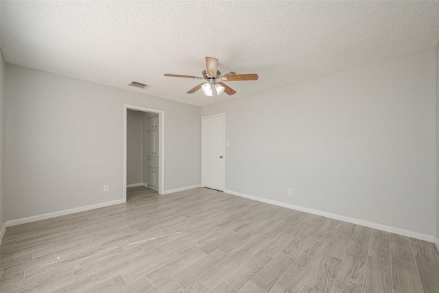 unfurnished room with visible vents, baseboards, ceiling fan, a textured ceiling, and light wood-type flooring