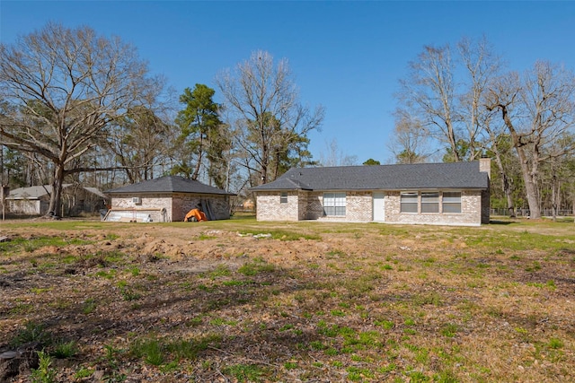 single story home with a front yard, a chimney, and an outdoor structure