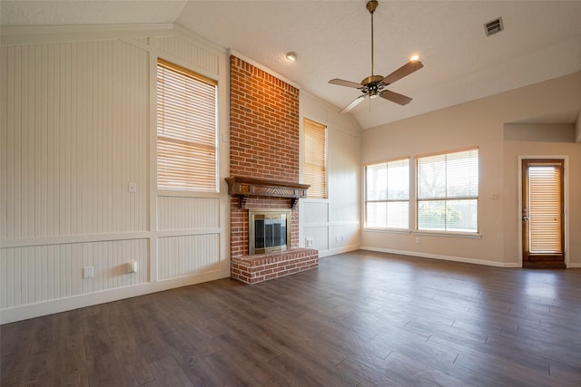 unfurnished living room with lofted ceiling, dark wood-type flooring, visible vents, a ceiling fan, and a brick fireplace