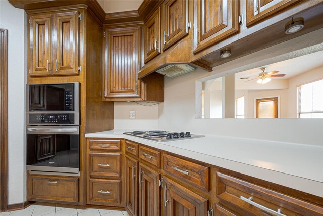 kitchen featuring brown cabinets, light tile patterned floors, stainless steel appliances, light countertops, and ceiling fan