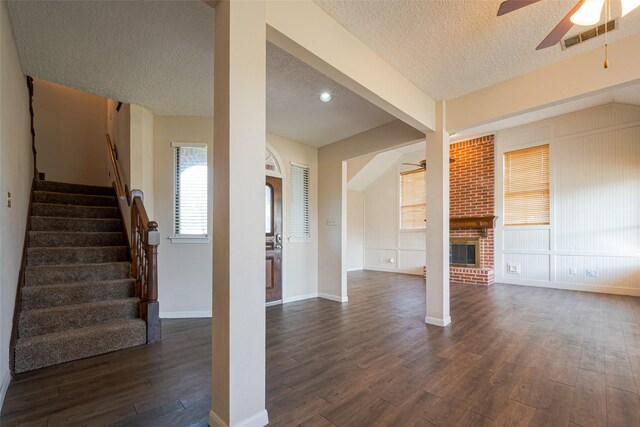 unfurnished living room featuring visible vents, dark wood-style floors, ceiling fan, stairway, and a textured ceiling