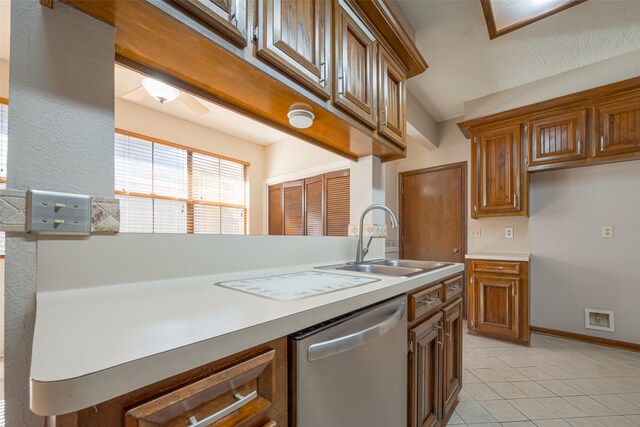 kitchen featuring a sink, light tile patterned floors, brown cabinetry, and stainless steel dishwasher