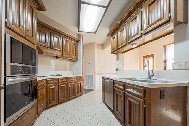 kitchen featuring a sink, visible vents, light countertops, appliances with stainless steel finishes, and brown cabinets