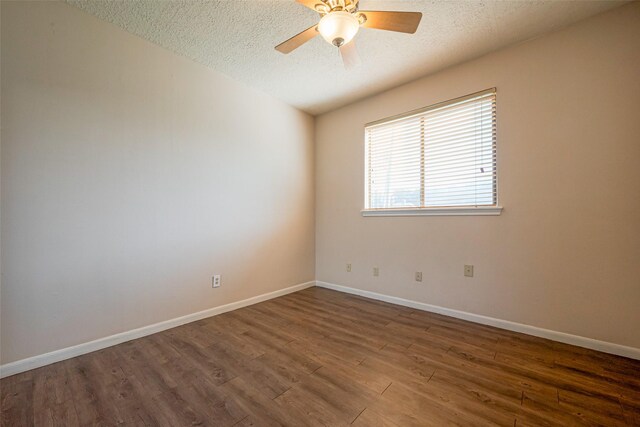 empty room with a textured ceiling, ceiling fan, wood finished floors, and baseboards