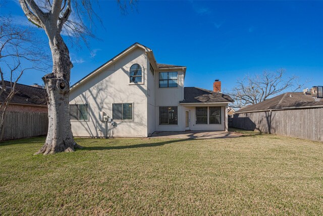 rear view of house featuring a patio area, a lawn, a chimney, and a fenced backyard