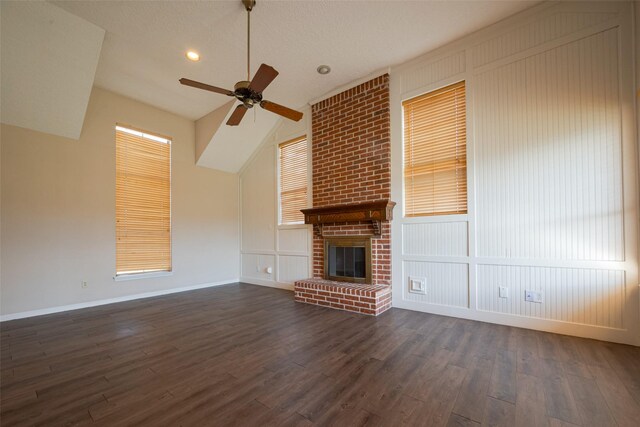 unfurnished living room with a high ceiling, dark wood-style flooring, a fireplace, a ceiling fan, and baseboards