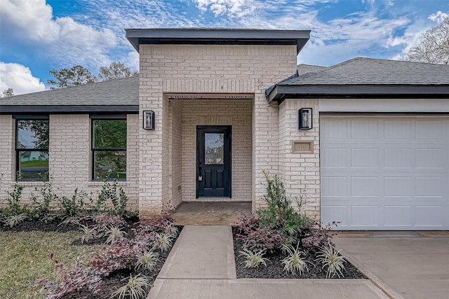 property entrance with a garage, brick siding, and a shingled roof