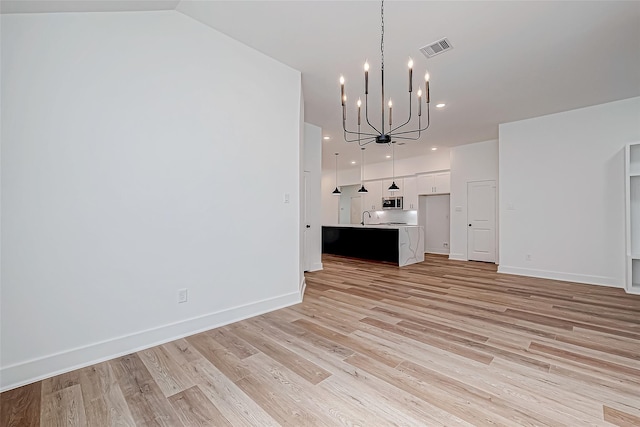 unfurnished living room featuring light wood-style flooring, recessed lighting, visible vents, baseboards, and an inviting chandelier