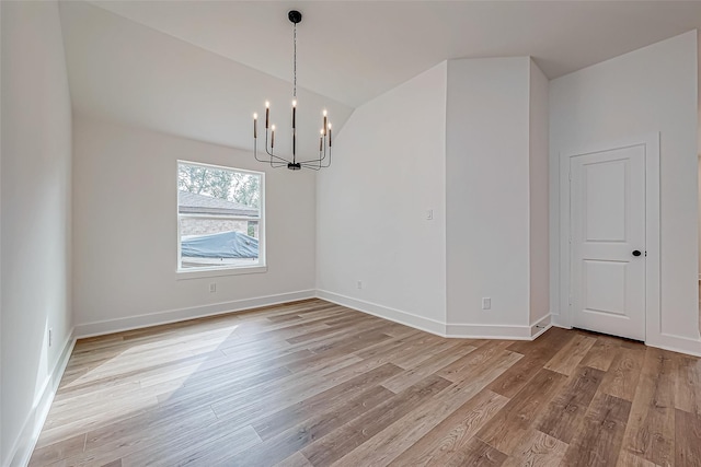 unfurnished dining area featuring light wood finished floors, baseboards, vaulted ceiling, and a notable chandelier