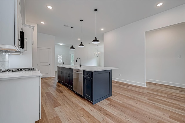 kitchen featuring light wood finished floors, decorative backsplash, dishwasher, an island with sink, and a sink