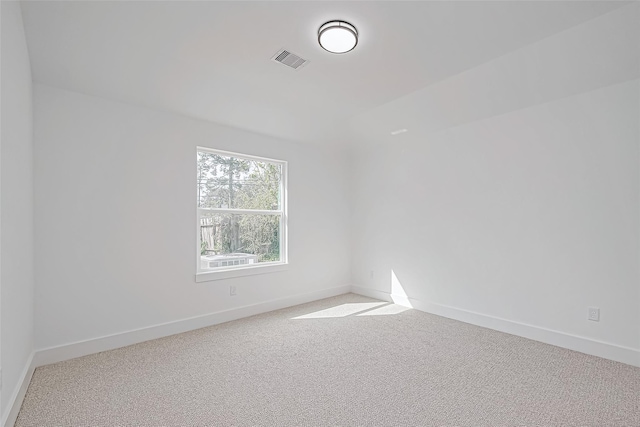 spare room featuring carpet, visible vents, and baseboards