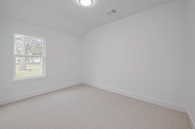 unfurnished room with visible vents, vaulted ceiling, light carpet, and baseboards