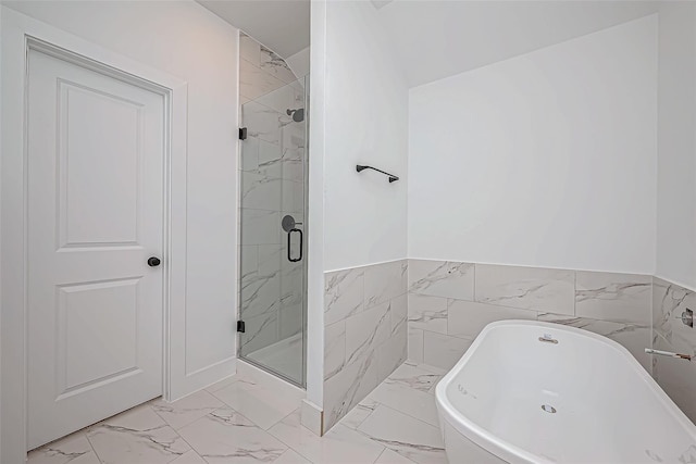 full bath featuring marble finish floor, tile walls, a freestanding bath, and a stall shower