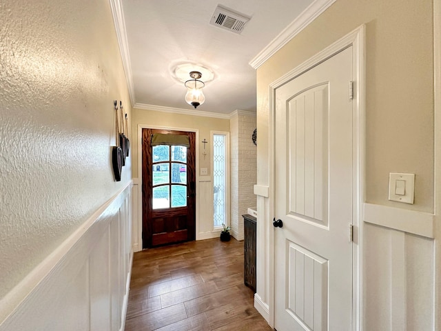 doorway featuring ornamental molding, wainscoting, visible vents, and dark wood-style floors