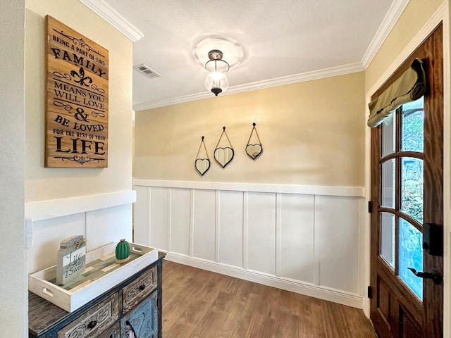 interior space with a wainscoted wall, crown molding, visible vents, and wood finished floors