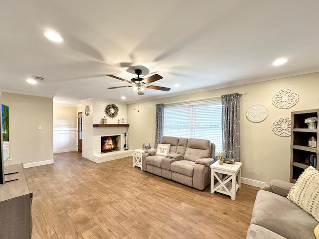 living area with crown molding, visible vents, a fireplace, and light wood-style flooring