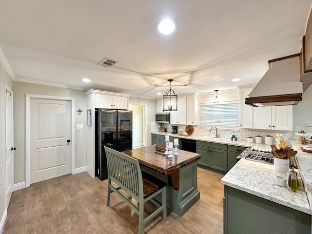 kitchen with visible vents, custom range hood, ornamental molding, black appliances, and a sink