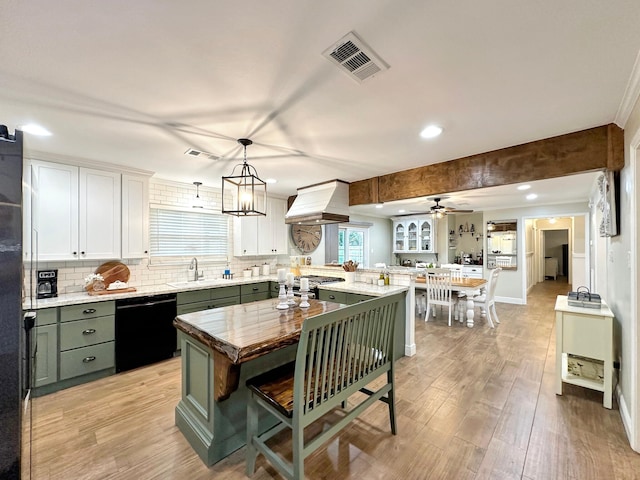 kitchen with a sink, visible vents, black dishwasher, custom range hood, and green cabinetry