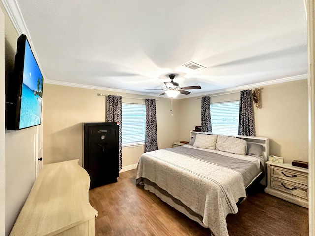 bedroom featuring wood finished floors, a ceiling fan, baseboards, visible vents, and crown molding