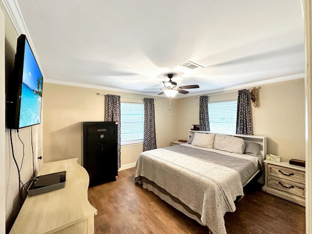 bedroom with ceiling fan, wood finished floors, visible vents, baseboards, and ornamental molding