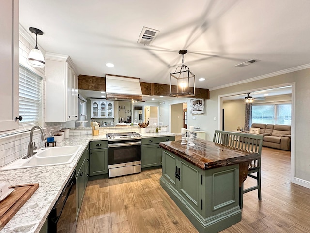 kitchen featuring visible vents, green cabinetry, gas range, light wood-style flooring, and a sink