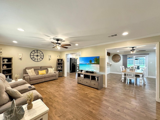 living area featuring visible vents, wood finished floors, and ornamental molding