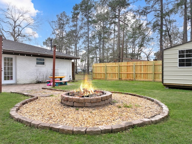 view of yard featuring an outdoor fire pit, fence, and an outdoor structure