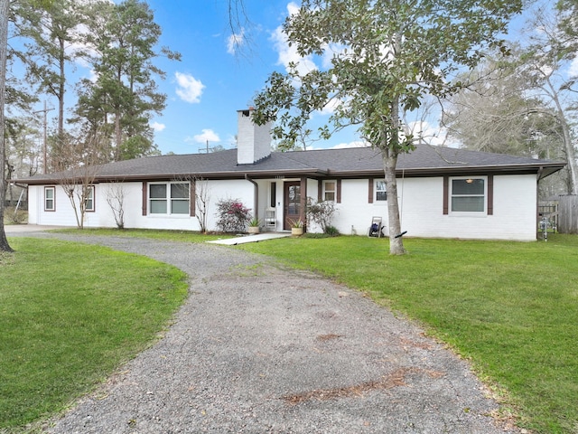 ranch-style home with gravel driveway, roof with shingles, a chimney, a front yard, and fence