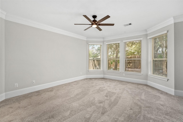 carpeted spare room featuring ornamental molding, a ceiling fan, visible vents, and baseboards