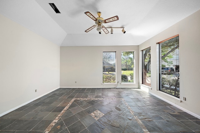 interior space with stone tile floors, baseboards, ceiling fan, and a textured ceiling