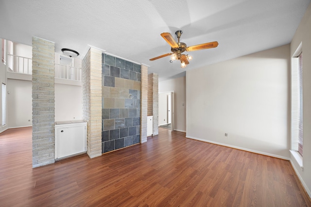 empty room with a ceiling fan, a fireplace, a textured ceiling, and wood finished floors