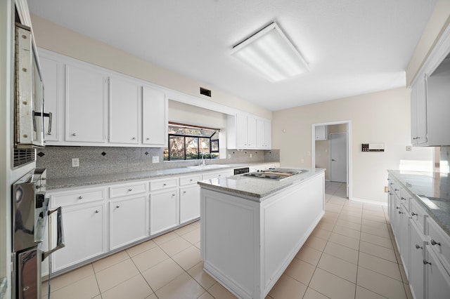 kitchen featuring light tile patterned floors, decorative backsplash, a sink, and a center island