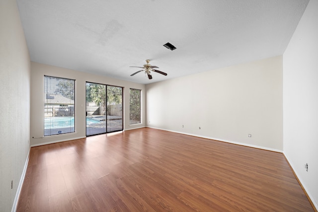 unfurnished room featuring ceiling fan, a textured ceiling, wood finished floors, and baseboards