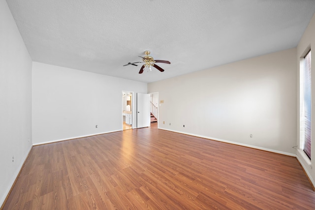 spare room with a ceiling fan, a textured ceiling, baseboards, and wood finished floors