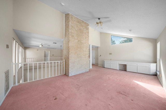 carpeted empty room with visible vents, high vaulted ceiling, built in study area, and a ceiling fan