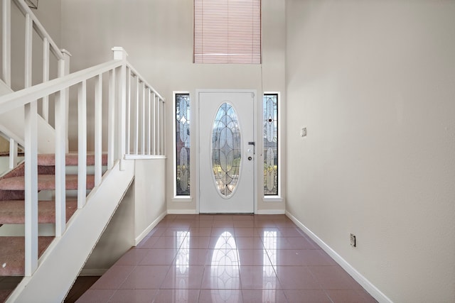 tiled foyer with a high ceiling, stairway, and baseboards