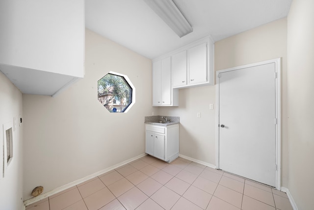 laundry room with light tile patterned flooring, a sink, cabinet space, and baseboards