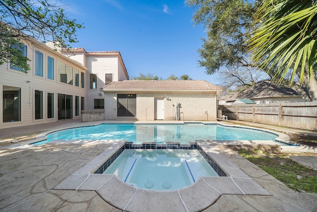 view of pool featuring a patio, fence, and a pool with connected hot tub