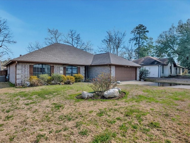 ranch-style house with a garage, brick siding, a shingled roof, concrete driveway, and a front lawn